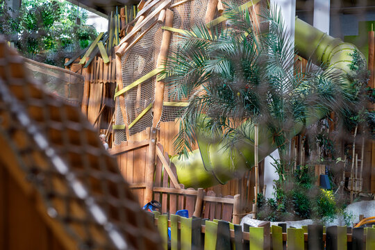 Vibrant indoor play area for children featuring a large green tube slide, wooden structures, and tro