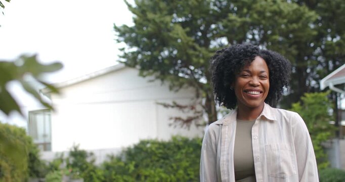 African American woman laughing, reacting to offcamera cue in yard, shirt leaves left, copy space