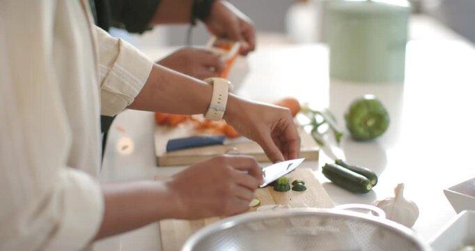 Meal prep is starting; two cooks are slicing zucchini and peeling carrots at counter for dinner
