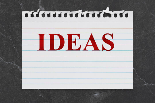 Ideas text on a white lined torn paper for your message on black stone
