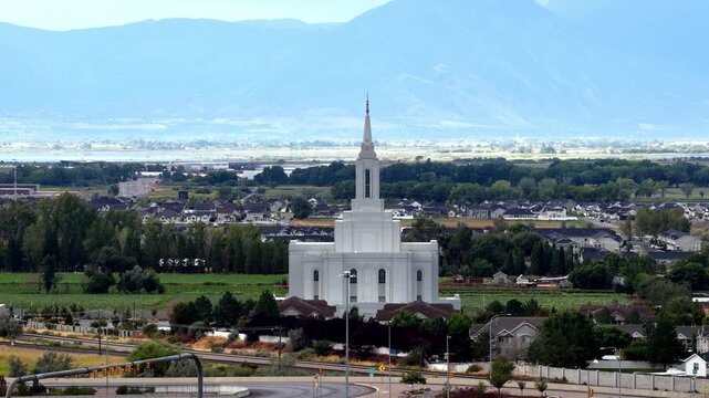 Orem, Utah, United States - 30 August 2026: Aerial view of the Orem Utah Temple surrounded by residential neighborhoods and green fields with mountains in the background.