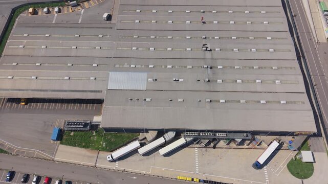 Sesto Ulteriano, Lombardia, Italy - 05 September 2026: Aerial view of the Esselunga Spa distribution center featuring a large industrial warehouse roof, loading docks, and parked semi-trucks.