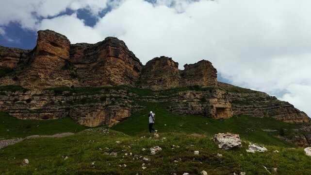 Woman walking on grassy mountain slope with backpack