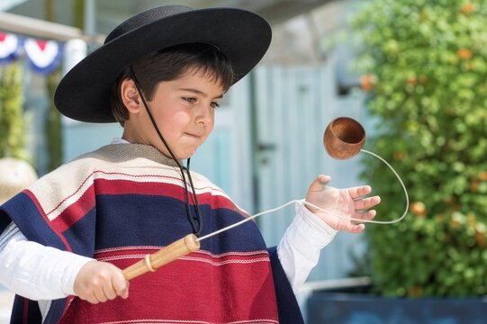 Chilean child concentrating while playing a traditional emboque game during Fiestas Patrias.