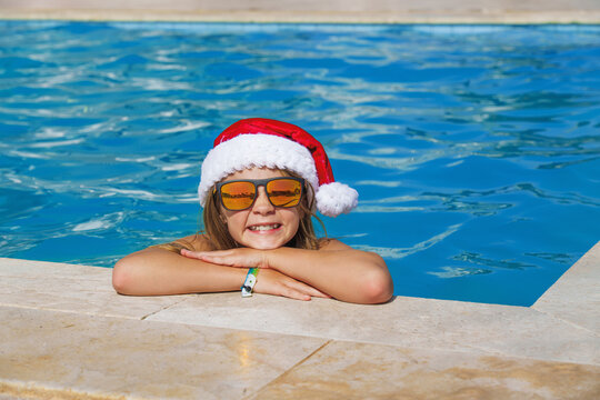 Christmas vacation on a tropical island. A happy girl child at a swimming pool at Christmas.