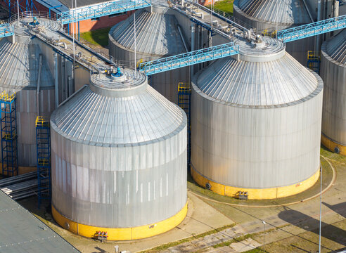 Aerial view of industrial metal storage tanks with yellow bases and connecting walkways at a wastewater treatment plant in Poland.
