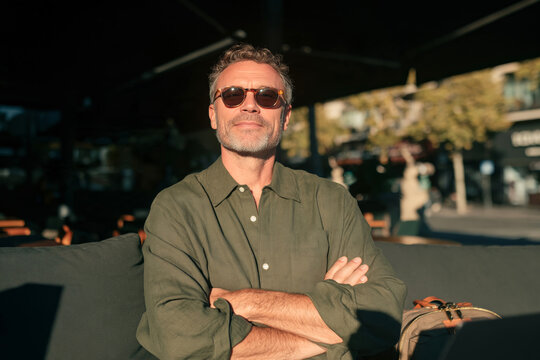 Portrait of Confident Mature Man with Gray Curly Hair and Glasses Outdoors in Summer