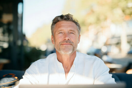 Portrait of Confident Mature Man with Gray Curly Hair and Glasses Outdoors in Summer
