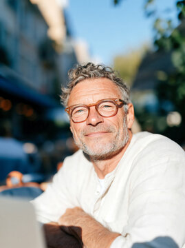 Portrait of Confident Mature Man with Gray Curly Hair and Glasses Outdoors in Summer