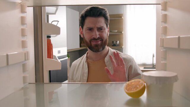 Dissatisfied hungry Caucasian man opening empty fridge shaking head no food disgusted male bachelor need delivery ordering meal smell gross odor lost appetite kitchen problem POV inside refrigerator