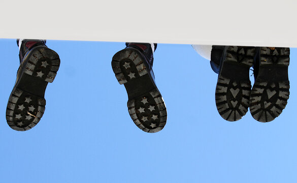 Pies con suela de zapato colgando en muro espacio editable texto y cielo azul