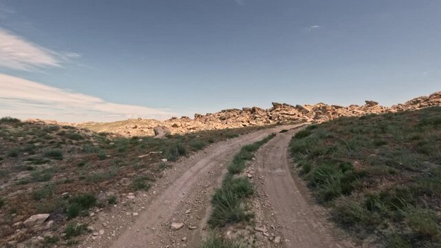 Forward tracking shot along dirt road in arid landscape