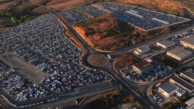Civitavecchia, Lazio, Italy - 23 August 2026: Aerial view of a vast automotive storage lot filled with rows of new vehicles near industrial facilities.