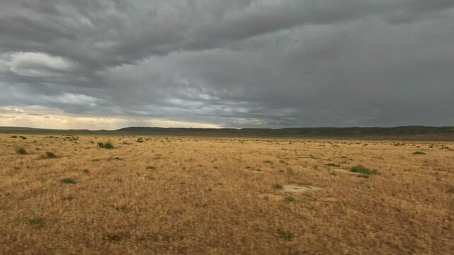 Camera pans across flat arid landscape under stormy sky