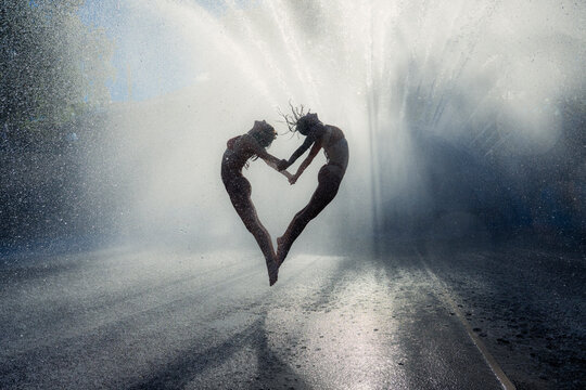 Two white women jumping and forming heart shape