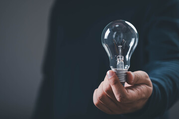 Business professional holding a clear light bulb, symbolizing ideas, creativity, innovation, opportunity, problem solving, leadership, strategy, technology, future growth, success, and inspiration. © Bordinthorn