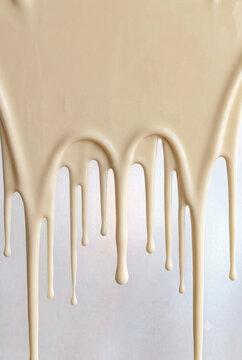 Thick milky-cream glaze or melted white chocolate flowing downward in smooth, glossy droplets against a clean, light surface. Perfect for dessert branding, bakery menus, dairy concepts, or rich cosmet