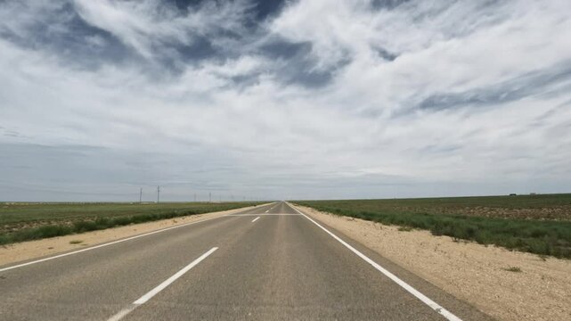 Driving forward on an asphalt highway through a flat landscape