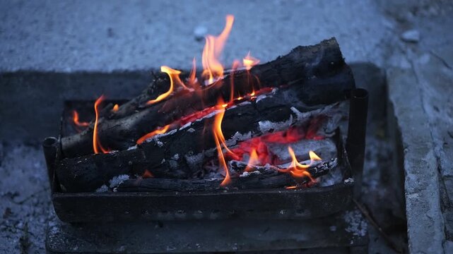 Burning logs in a small brazier creating a warm campfire ambiance