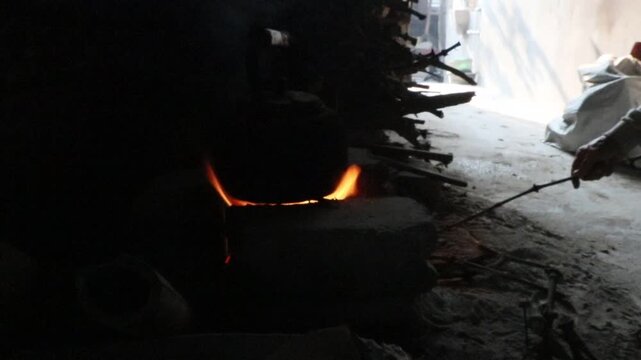 Traditional wood-fired stove heating water in a rustic rural kitchen, with burning branches beneath a cooking pot, showcasing traditional cooking and simple living.