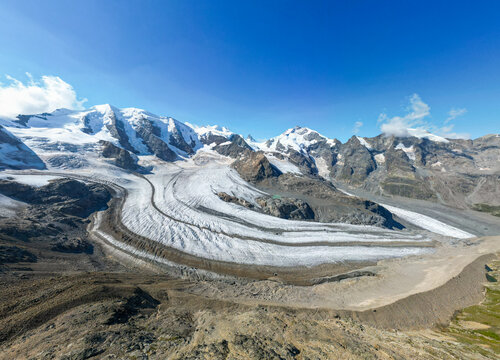 Aerial view of Pers Glacier with Piz Bernina and Piz Palu, showcasing the dramatic ice formations, rocky moraines, and snow-capped peaks in Pontresina, Grisons, Switzerland.