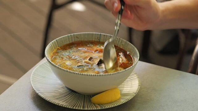 Person squeezing lemon and stirring seafood soup