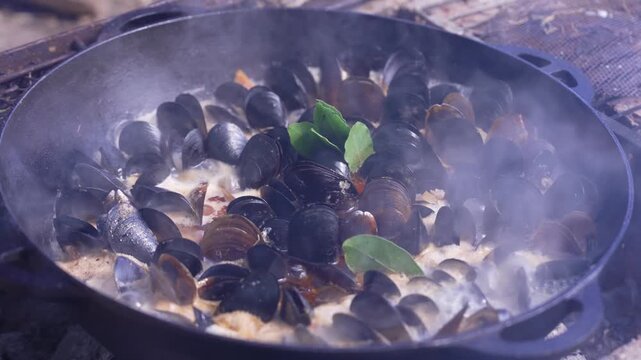 Festival food. Mussels cooked in a large cauldron over an open wood fire