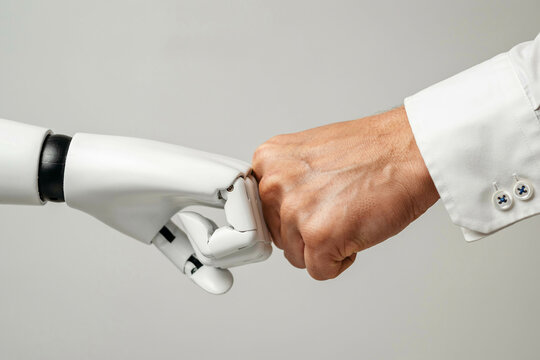 Robot and human hand fist bump represents future partnership between ai and person.