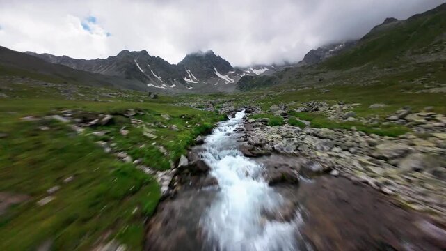 Fast forward aerial tracking shot over a rocky alpine river