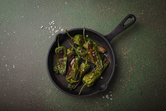 Padron peppers fried cast iron skillet sea salt dark green background Spanish appetizer top view
