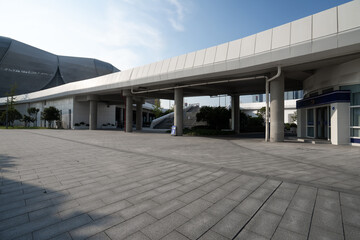 Obraz premium Modern architectural plaza with gray paved ground and columns under blue sky