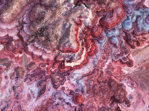 Aerial view of Hanksville Bentonite Hills featuring vibrant red, purple, and grey clay layers with intricate erosion patterns in Hanksville, Utah, United States.