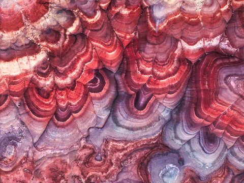 Aerial view of the colorful, layered clay formations of the Hanksville Bentonite Hills, showcasing vibrant red, purple, and white bands in the desert landscape of Hanksville, Utah, United States.
