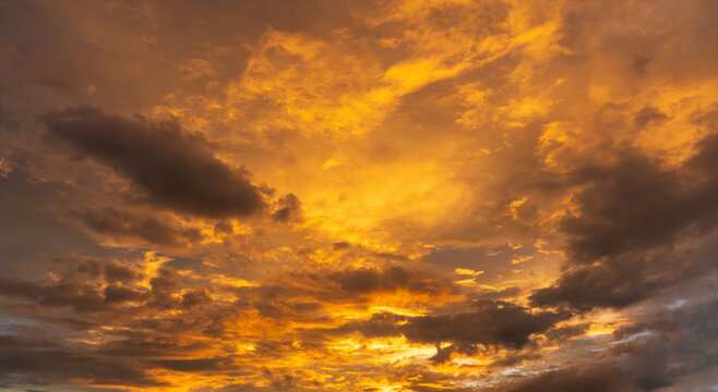Vibrant golden sunset sky filled with dramatic clouds glowing in orange light. Beautiful background for nature and sky texture.