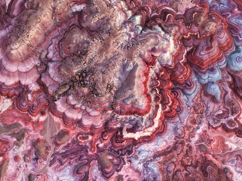 Aerial view of Hanksville Bentonite Hills featuring vibrant red, purple, and white clay layers with intricate erosion patterns and rugged desert terrain Hanksville, Utah, United States.