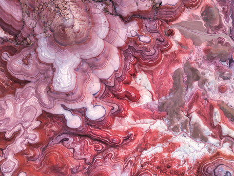 Aerial view of the colorful, layered clay formations of the Hanksville Bentonite Hills, showcasing intricate red, purple, and white geological patterns in Hanksville, Utah, United States.
