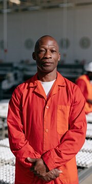 Male production worker portrait wearing orange coverall at poultry processing facility for industrial background and workforce recruitment banner design