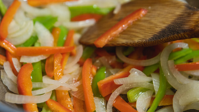 cebolla, pimiento rojo, pimiento verde salteados en un wok a fuego alto