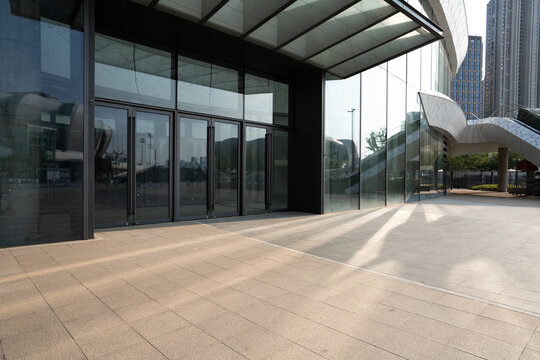 modern glass curtain wall building entrance plaza with sunlight and shadows