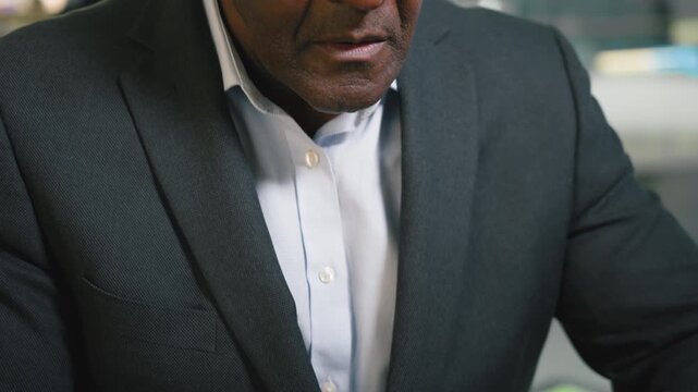 Close up serious 50s African American business man working with laptop technology online job work with application mature businessman male boss browsing computer device messaging with email indoors