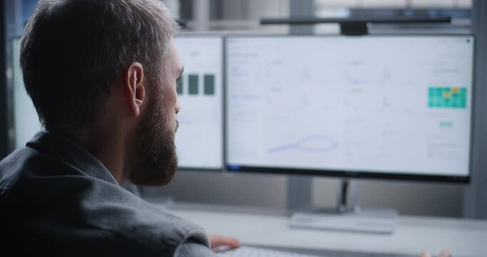 Data Center Technician Monitors Server Systems After Critical Overheating Alert, Analyzing Systems on Dual Screens to Resolve Issues, Protect Hardware, Maintain Uptime, and Ensure Reliable Service.