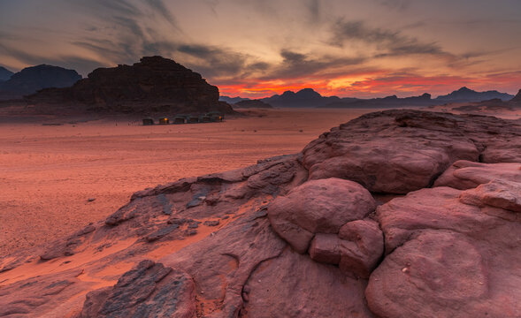 View of the Wadi Rum Protected Area at sunset, featuring dramatic red sandstone rock formations and a vast desert landscape in Wadi Rum Village, Aqaba Governorate, Jordan.