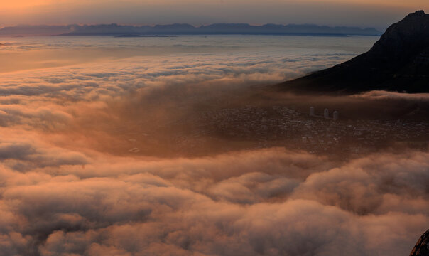 View of the sunset light over the clouds covering the city with Lion's Head visible in the distance, Cape Town, Western Cape, South Africa.
