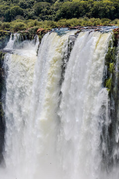 View of the powerful Iguazu Falls surrounded by lush tropical vegetation and mist in Iguazu National Park, Puerto Iguazu, Misiones, Argentina.