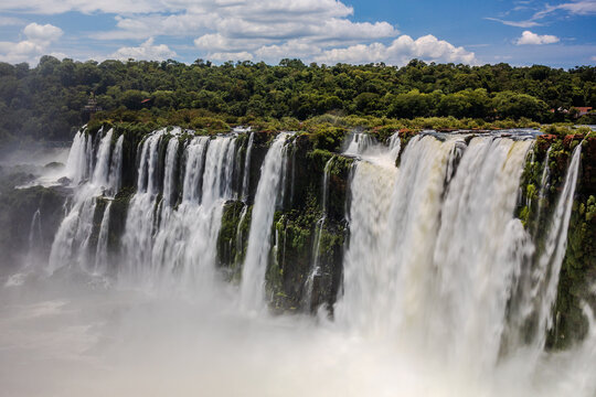 View of the powerful cascades of Iguazu Falls within the lush rainforest of Iguazu National Park, with mist rising from the water above Puerto Iguazu, Misiones, Argentina.