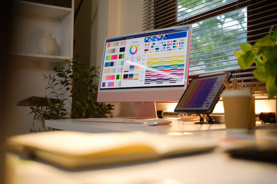 Modern creative workspace with digital displays showing colorful design references.