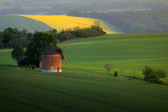 View of the historic windmill standing in the lush green fields of the rolling countryside in Chvalkovice, South Moravian Region, Czechia.
