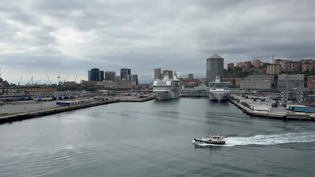 26 April 2026, Italy, Liguria, Genoa, Port Cruise Terminal - Pilot boat escorting MSC World Europa overlooking Moby Aki and GNV Rhapsody fast ferry moored on overcast day