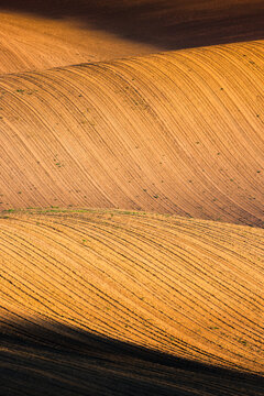 View of rolling agricultural fields with textured soil patterns and dramatic light and shadow in Brno, South Moravian Region, Czechia.