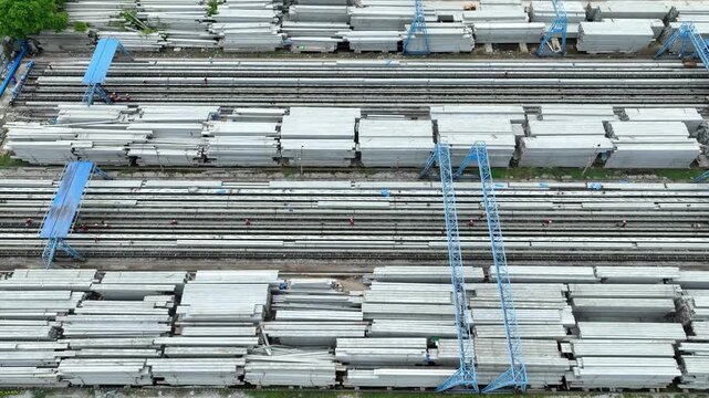 Top down view shows rows of concrete columns inside a manufacturing facility, symbolizing standardized production, construction efficiency and modern engineering.
